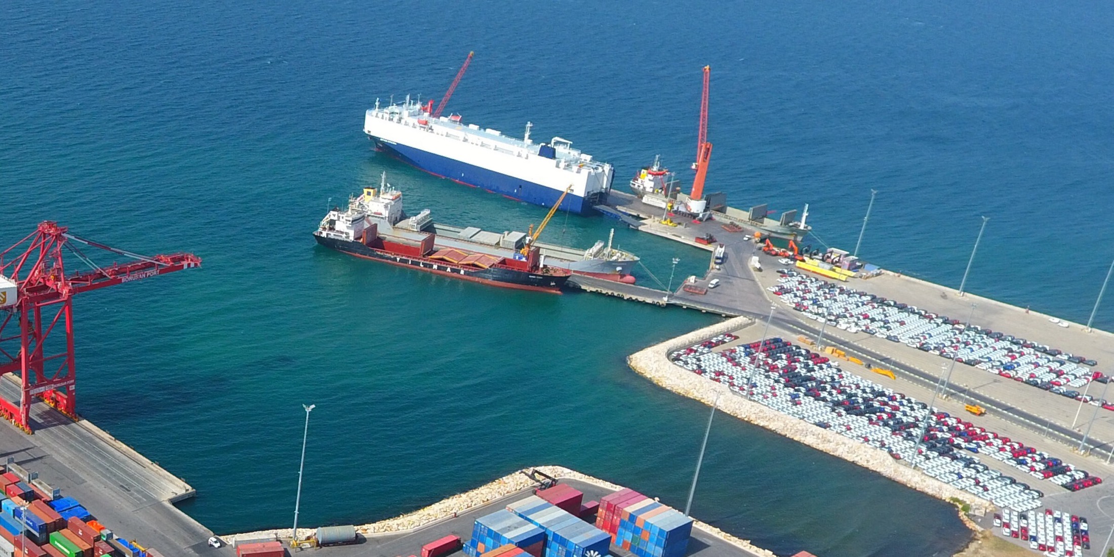 Aerial view of a port with cranes, container stacks and vessels alongside