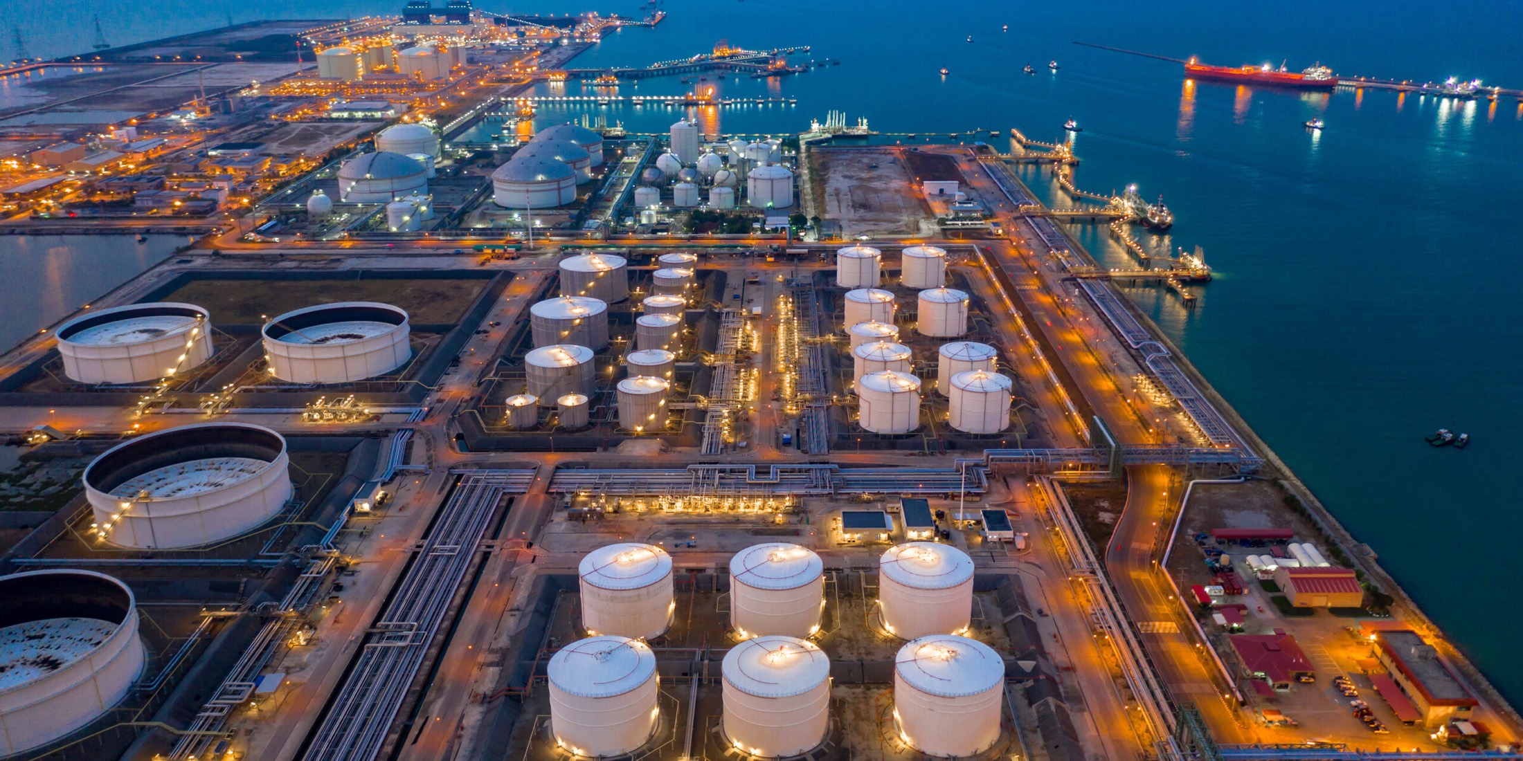 An energy terminal at dusk, with a tanker berthed at the jetty
